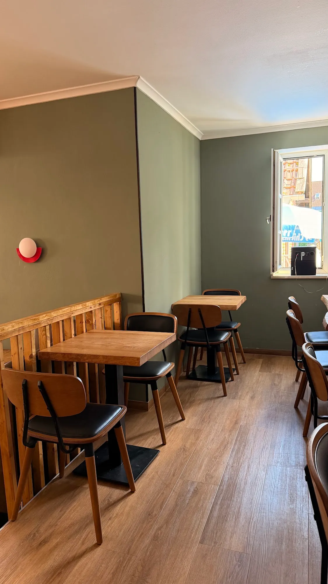Gastraum der Elivaria Eatery mit hellem Holzboden, salbeigrünen Wänden und Holztischen