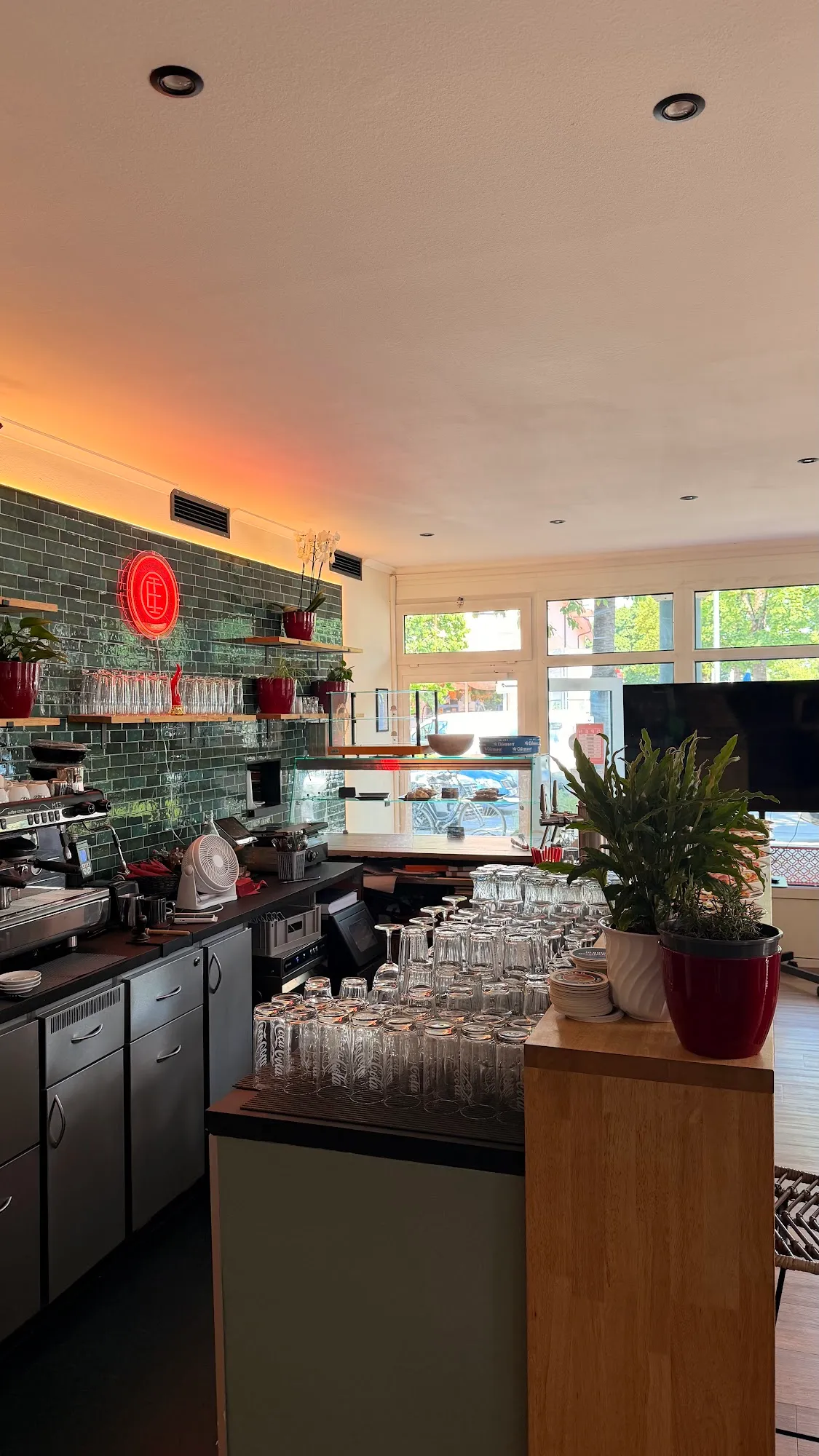 Theke der Elivaria Eatery mit dunkelgrünen Fliesen, rotem Leuchtsiegel und Espressomaschine